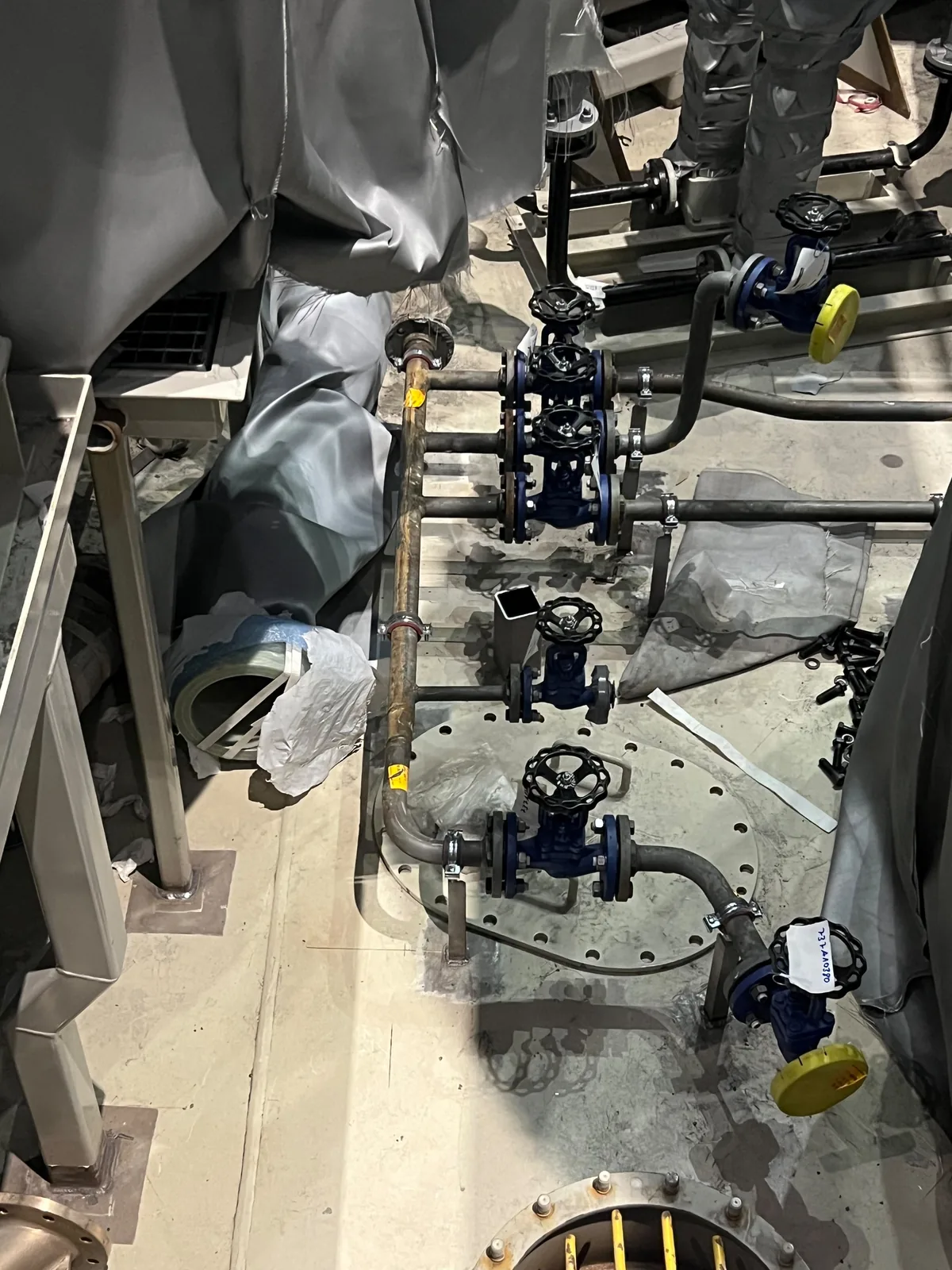 Gruppo valvole disposto attorno a un passo d’uomo imbullonato, con i coperchi lasciati liberi e ogni estremità aperta tappata