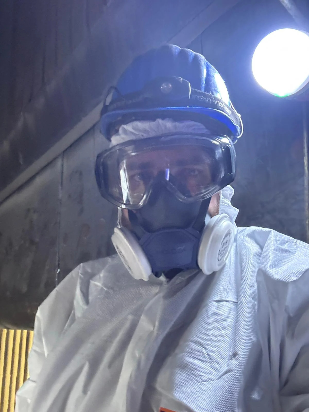 Arbeiter mit Schutzhelm, Schutzbrille und P3-Atemschutz im kalten Feuerraum eines Müllheizkraftwerks